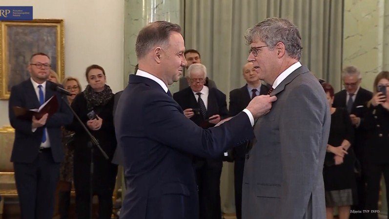 Ceremony featuring a formal award presentation by a leader, with attendees observing in a dignified setting.
