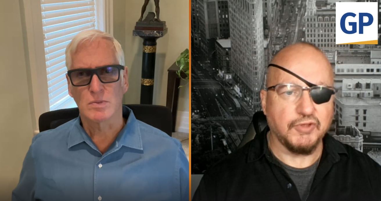 Two men engaged in a conversation, one wearing glasses and the other an eye patch, with a cityscape backdrop and indoor setting.