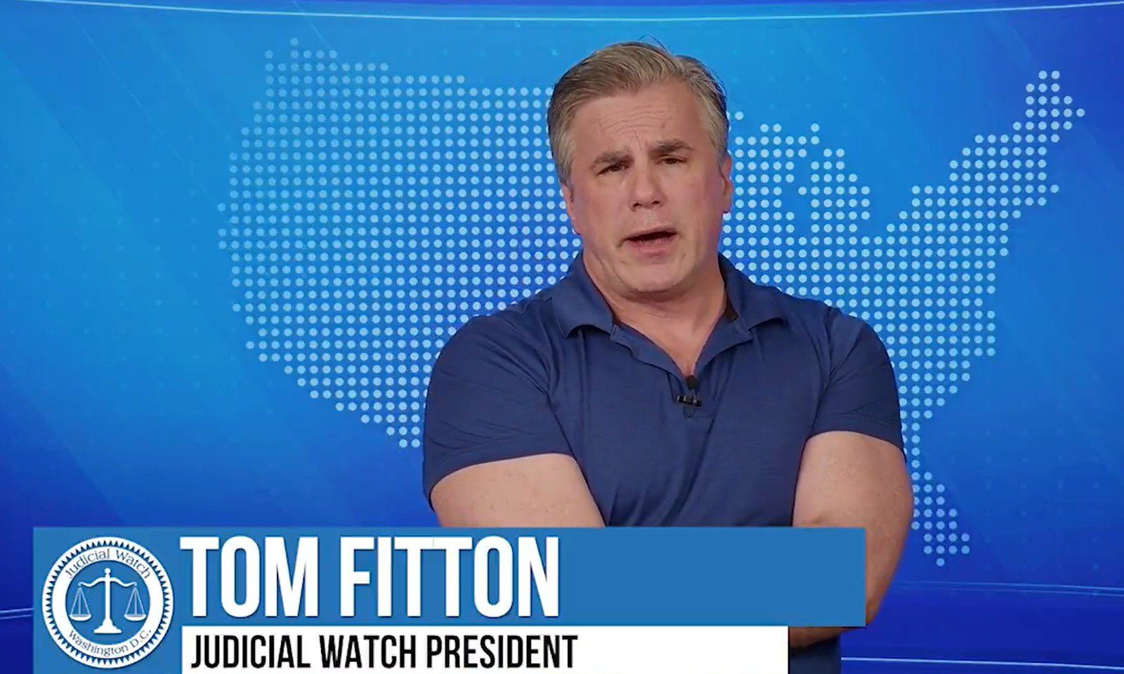 Tom Fitton, President of Judicial Watch, discusses legal and political issues against a blue backdrop with a map design.