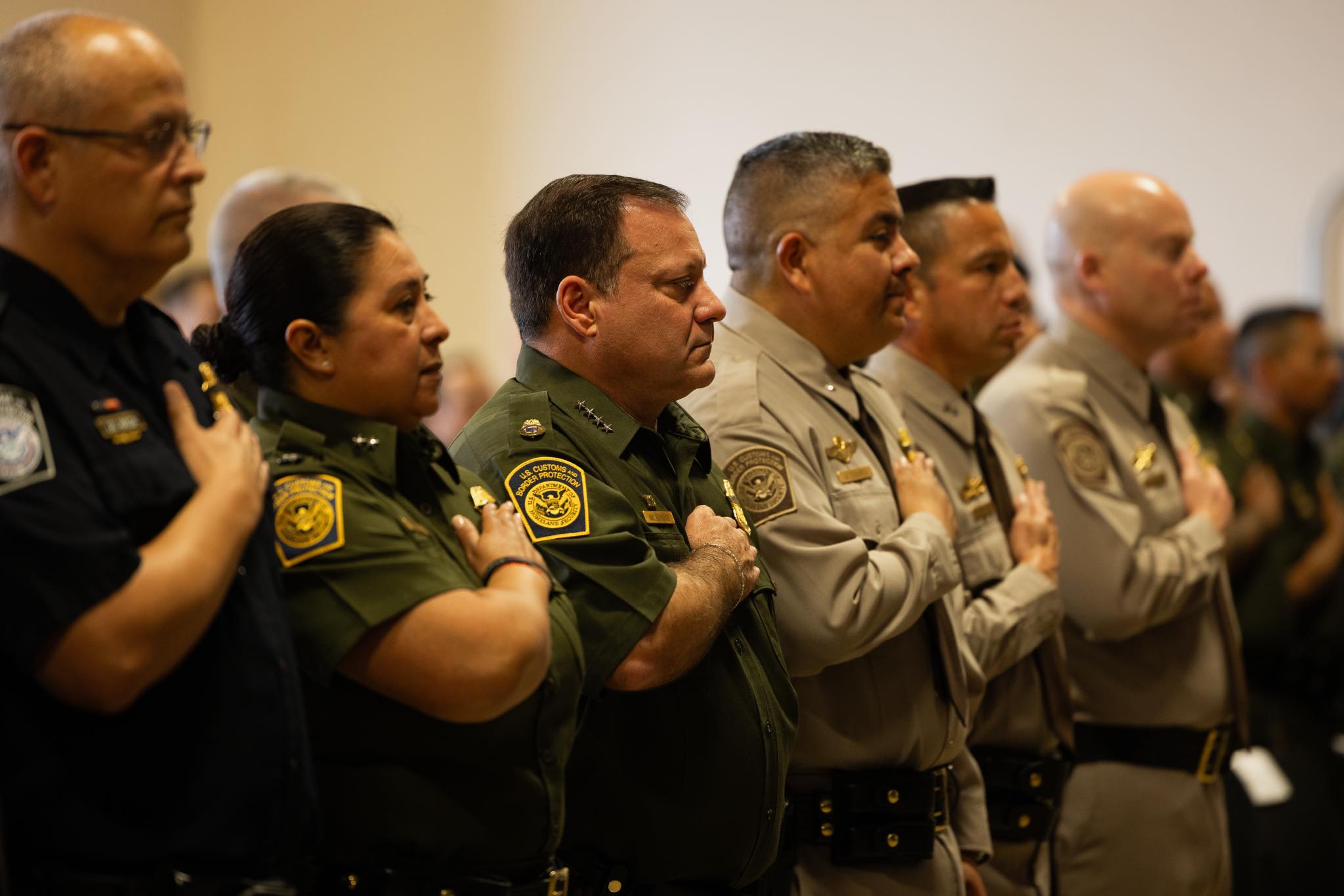 Law enforcement officers standing in formation with hands over hearts during a formal ceremony, showcasing unity and respect.